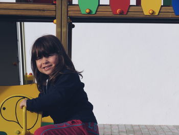 Side view portrait of girl sitting on play equipment