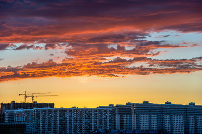 Aerial view of buildings against dramatic sky during sunset