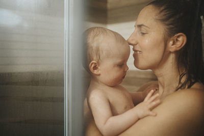 Mother showering with baby at home