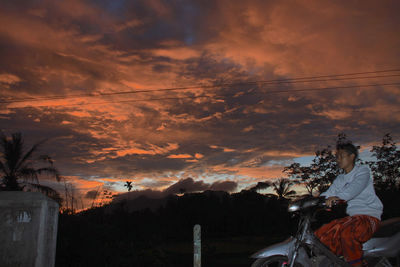 Low angle view of dramatic sky over cityscape during sunset