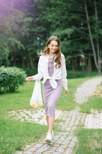 A happy girl walks through the park with an eco-friendly reusable fruit bag. green life