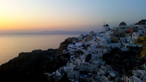 High angle view of buildings by sea against sky during sunset