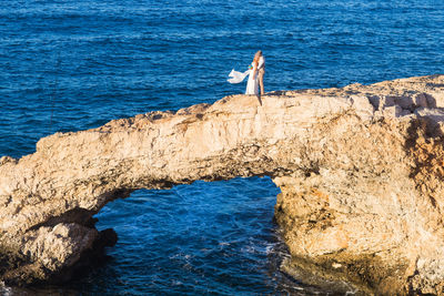 Side view of man standing on rock by sea