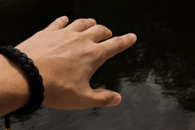 Cropped hand gesturing against pond