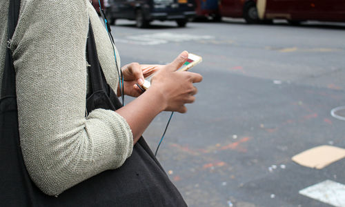 Midsection of man using mobile phone in city