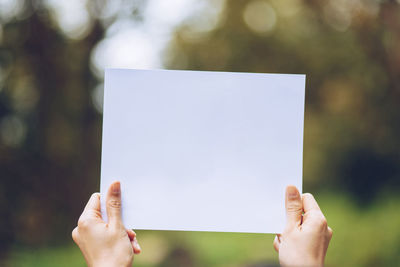 Close-up of hand holding paper against blurred background