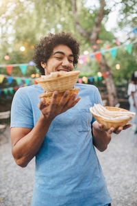 Smiling young man carrying food in bowls during dinner party in backyard