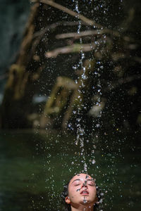 Teenage girl standing under splashing water