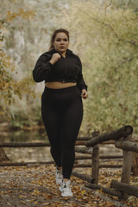 Determined overweight young woman jogging in autumn park