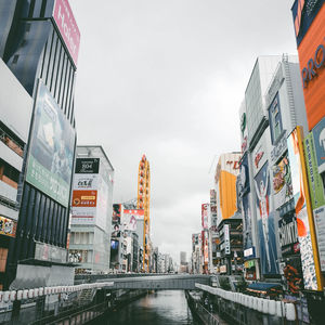 Low angle view of bridge amidst buildings against sky