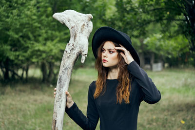 Portrait of young woman standing against trees