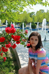 Portrait of young woman standing by flowering plants