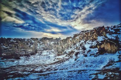 Snow covered landscape against dramatic sky