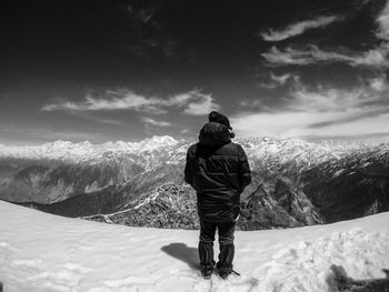 Rear view of man looking at mountains against sky