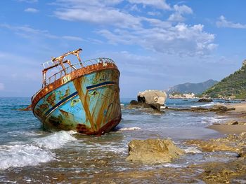 Abandoned boat on beach against sky