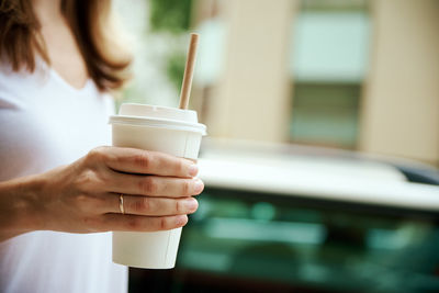 Woman holds paper coffee cup at city street