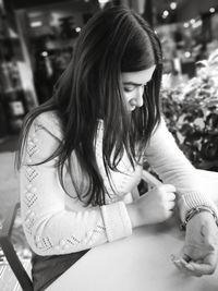 Woman looking at sweater sleeve in cafe