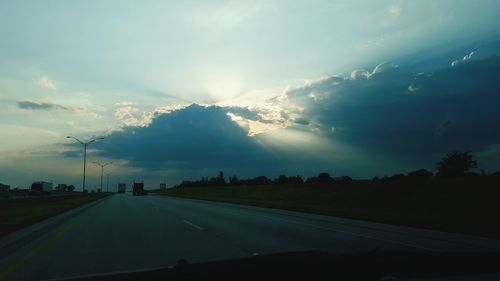 Cars on road against cloudy sky