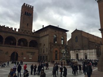 Tourists in city against cloudy sky