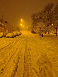 Snow covered street against sky at night