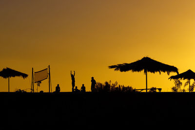 Silhouette birds on landscape against sky during sunset