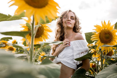 Portrait of woman standing by sunflowers