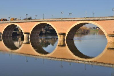 Arch bridge over river against clear sky