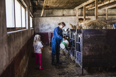 Grandmother with granddaughter in cowshed