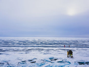 People standing on snow covered beach