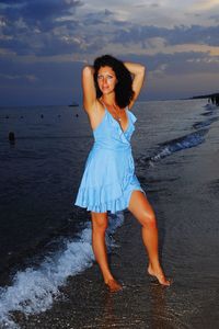 Full length of woman standing at beach against sky