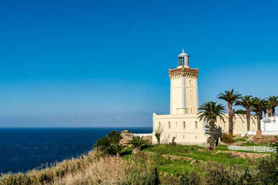 Lighthouse by sea against sky