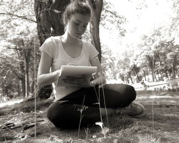 Girl sitting on table against trees