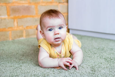 Portrait of smiling little caucasian baby girl in yellow dress with wooden teething toy. 