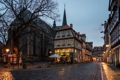 Street amidst buildings in city at dusk