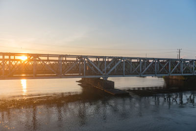 Bridge over river against sky during sunset