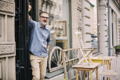 Portrait of owner standing with hand on hip at antique shop