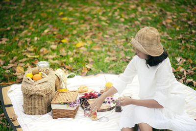 Woman sitting on blanket at park with fruits