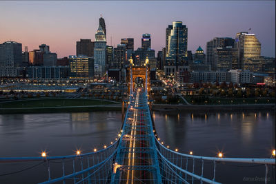 Illuminated bridge over river against sky at night