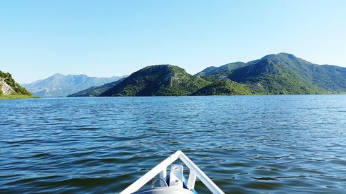 Cropped image boat sailing in sea by mountains against clear sky