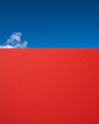 Low angle view of red wall against blue sky