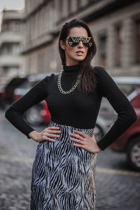 Fashionable woman standing on footpath in city