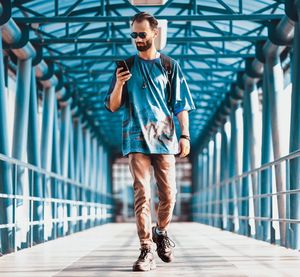 Full length portrait of man standing on footbridge