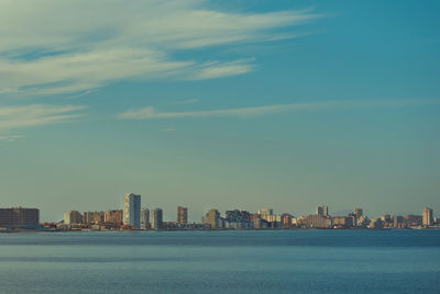 Sea by cityscape against sky