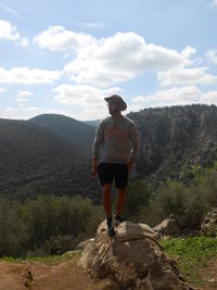 Rear view of man standing on mountain against sky