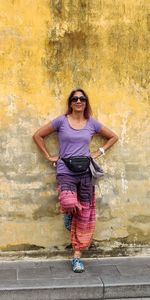 Full length of smiling woman standing against ancient wall