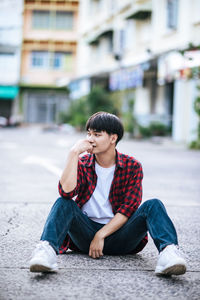 Young woman sitting on street in city