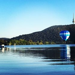 Boats in lake against clear blue sky