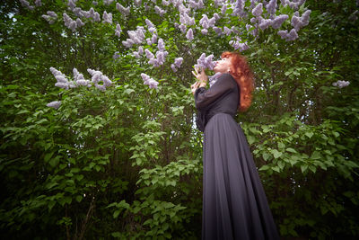 Low angle view of woman standing by flowering plants