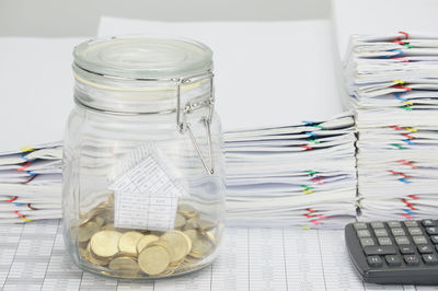 Close-up of glass jar and documents on table