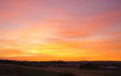 Scenic view of silhouette field against orange sky